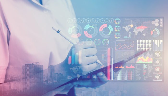 Dottore in camice bianco scrive su tablet digitale con grafici interattivi sovrapposti. Rappresentazione della gestione digitale dei dati sanitari.