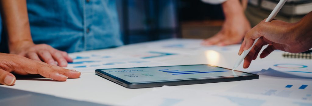 Mani di candidati che analizzano dati e grafici digitali su tablet durante un colloquio di lavoro